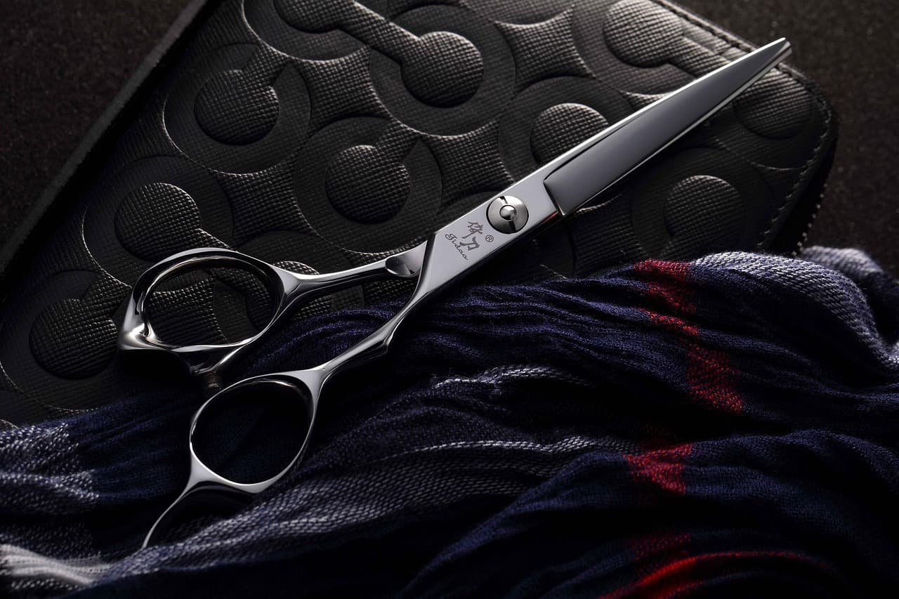 Barber's scissors resting on a dark cape
