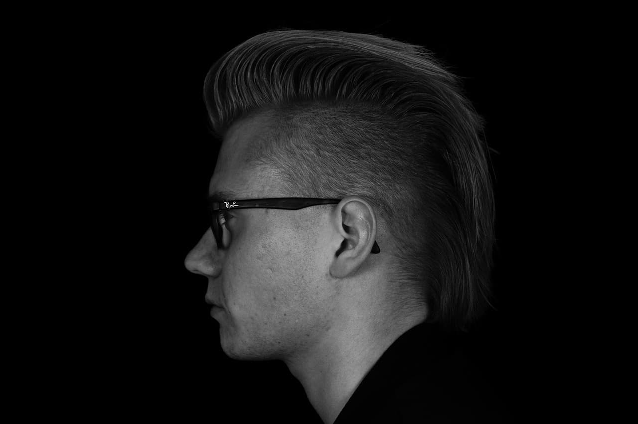 A man in profile with short sides and a swept-back top, in black and white